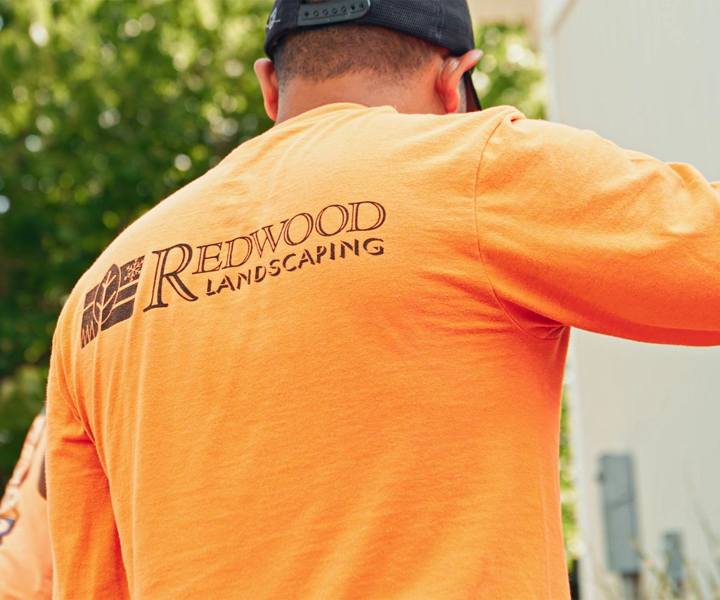 A Redwood Landscaping crew member in a branded shirt on a Greater Lansing job site